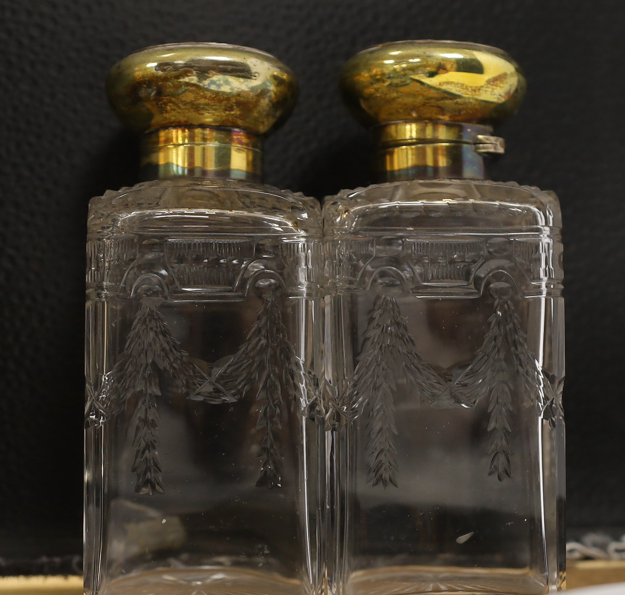 A pair of George V silver gilt mounted cut and etched glass square scent bottles and stoppers, Goldsmiths & Silversmiths Co Ltd, London, 1911, 15cm.